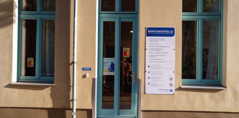 Eingangsbereich Pflegestützpunkt Spreestraße mit türkiser Tür in gelbem Haus