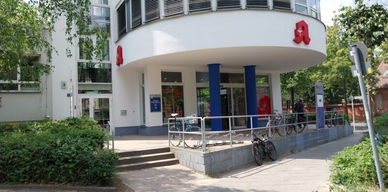 Zu sehen ist der Eingang zum Pflegestützpunkt Reichenberger Straße 3 in Hohenschönhausen. Der Eingang befindet sich links neben der Apotheke.